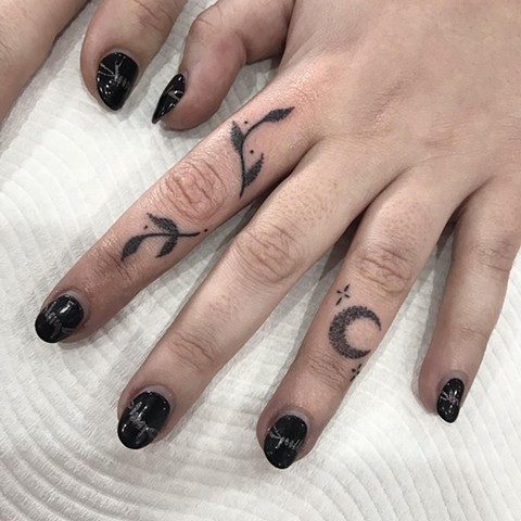 Finger tattoo adornments by Amy Jones Leaves with Crescent Moon and tiny star sprites. Black ink tattoo on hand. Female Tattoo artist located in Melbourne. Safe space for everyone. 