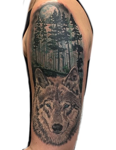 A tattoo of a Wolf in the woods, looking at the viewer. 