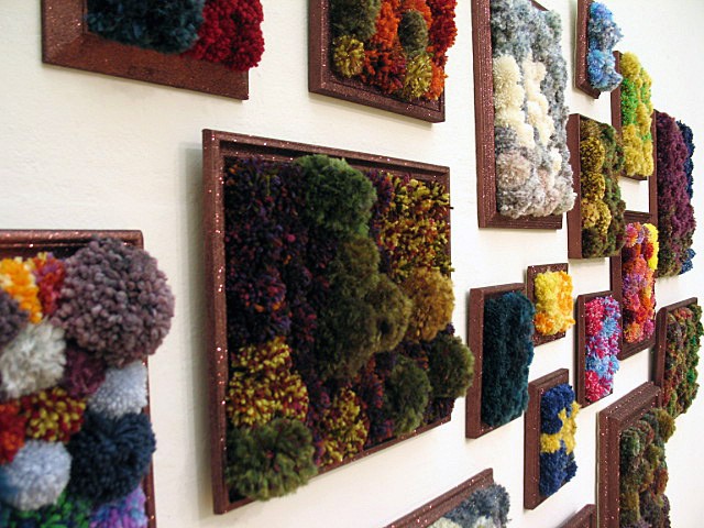 sculpture installation of brown glittered picture frames and multicolored yarn pom poms by Holly Campbell