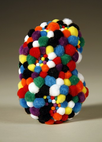 kidney shaped found rock covered in rainbow pom-poms by Holly Campbell