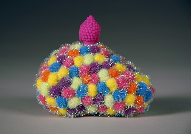 found rock sculpture covered in day glo sparkly pom poms with silicone buddah head on top by Holly Campbell