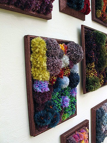 sculpture installation of brown glittered picture frames and multicolored yarn pom poms by Holly Campbell