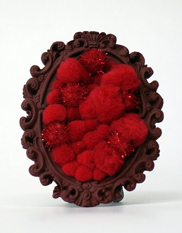 found oval picture frame sculpture painted filled with rainbow colored shiny red pom poms by Holly Campbell