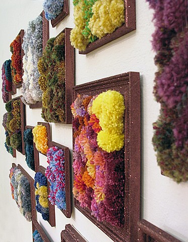 sculpture installation of brown glittered picture frames and multicolored yarn pom poms by Holly Campbell