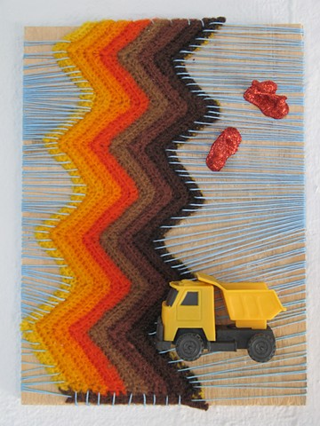 ready-made toy truck and construction worker toy figures covered in glitter and sitting on a yarn wrapped piece of wood by Holly Campbell