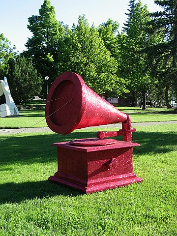 giant fuchsia glittered phonograph sitting on grass with gold beaded string sculpture by Holly Campbell