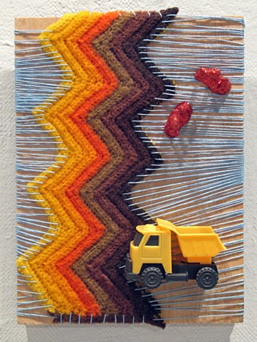 ready-made toy truck and construction worker toy figures covered in glitter and sitting on a yarn wrapped piece of wood by Holly Campbell