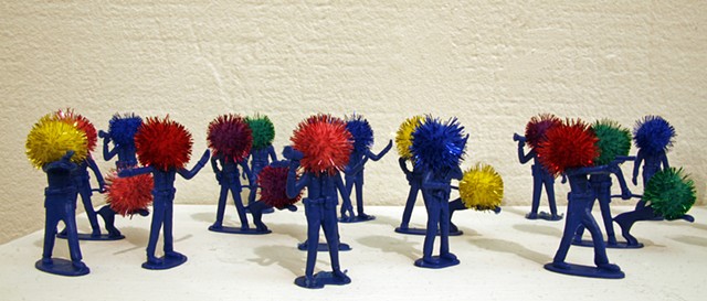 plastic police officer toy sculptures with shiny rainbow pom poms heads shelf by Holly Campbell
