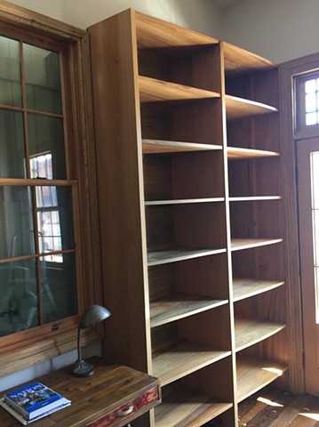 Sinker cypress corner bookshelves in historic New Orleans home. The shelves curve from the door to the window from 20" to 12". The end wall by the window is angled at 10 degrees to make the cabinet more sculptural. 