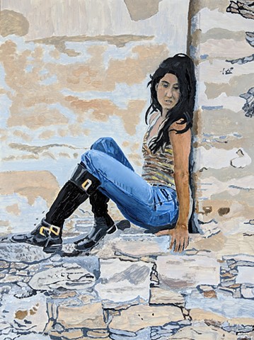 Portrait of woman in blue jeans, seated against a rock wall