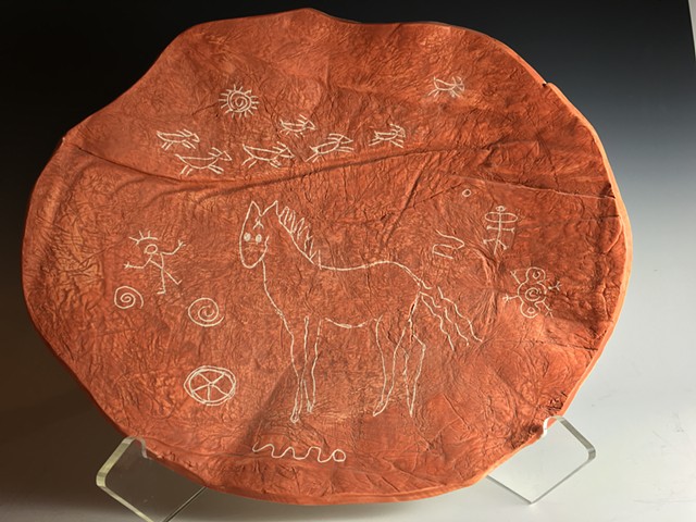 Ceramic plate incised with petroglyphs glazed black on back.