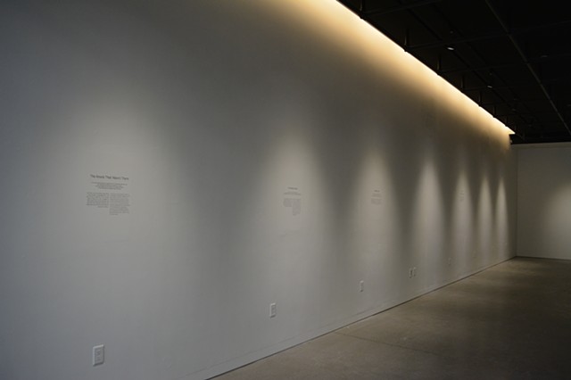 The image shows the left wall. There are seven lights focused on the wall at where one would expect a painting. The stories are engraved into the wall at different heights. Some at the highest points and others at the lowest points of the wall.