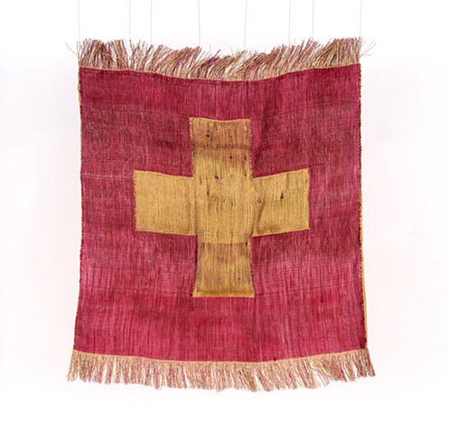 A textile with a gold cross with a red background and fringe at the top and bottom against a white background.