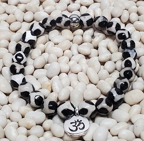 Handmade stretch bracelet with 8mm black and white leopard pattern Tibetan agate beads, with silver om charm. Tibetan Agate encourages strength, power, stability, and courage with grounding qualities. Made with care on double-strung 0.7mm stretch cord for