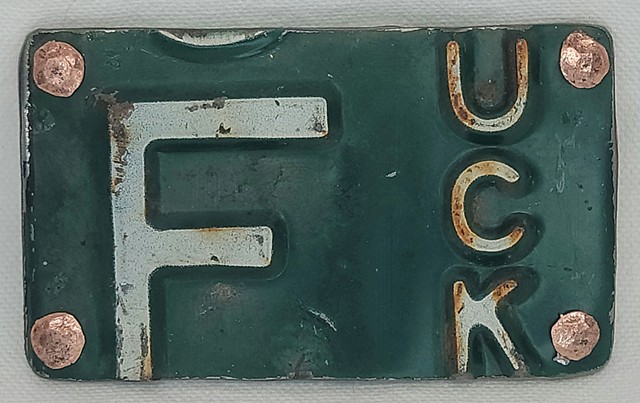 Interchangeable handmade belt buckle made from recycled license plate and hand-hammered copper rivets. Each buckle is unique and one-of-a-kind. Fits a snap type belt 1.5-1.75". White lettering on black background. Each buckle comes in a handmade grey felt