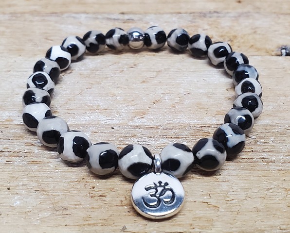 Handmade stretch bracelet with 8mm black and white leopard pattern Tibetan agate beads, with silver om charm. Tibetan Agate encourages strength, power, stability, and courage with grounding qualities. Made with care on double-strung 0.7mm stretch cord for