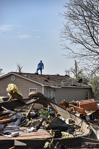 A resident of Silver City, Miss. stands on top of his house to survey the surrounding damage following a deadly tornado that ripped through the state Friday night.