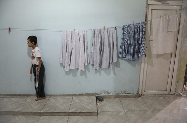 Bashir waits patiently as clothes dry indoors and dinner cooks.
