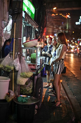 A group of sex workers stop by a roadside food cart in Bangkok, Thailand.