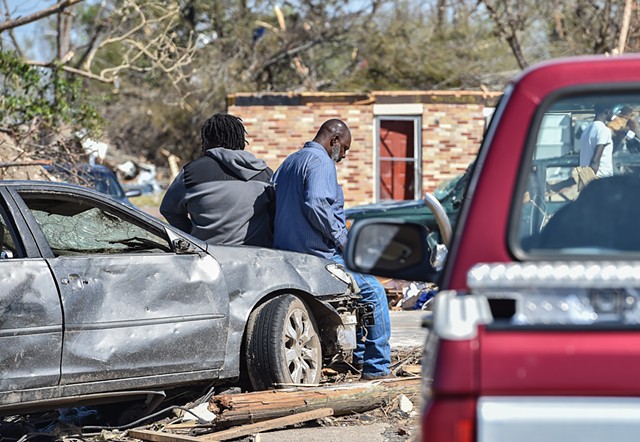 Two residents rest on a car hood following Friday’s violent tornado in Rolling Fork, Miss., Monday, March 27, 2023.