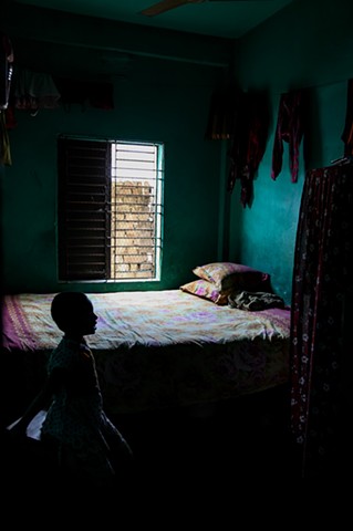 A sex worker's young child sits in his mother's empty room at the Rathkhola Brothel in Faridpur, Bangladesh.