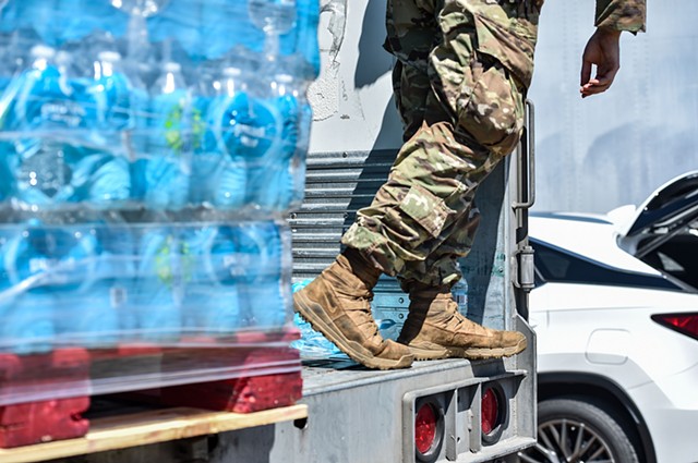 Mississippi Army National Guard soldiers unload cases of water from a trailer near Davis Road Park at a water distribution site in Byram, Miss., Thursday, September 1, 2022.