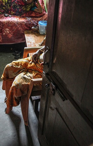 A madam sits in the doorway of one of her workers' rooms at the Rathkhola Brothel in Faridpur, Bangladesh. "Bonded" sex workers must pay their madam until the girls' original purchase price, paid by their former guardian, is paid back to the madam.