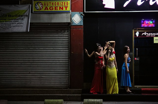 A group of young and colorful dancers take a quick break outside of Arexus KTV Bar in Manila, Philippines.