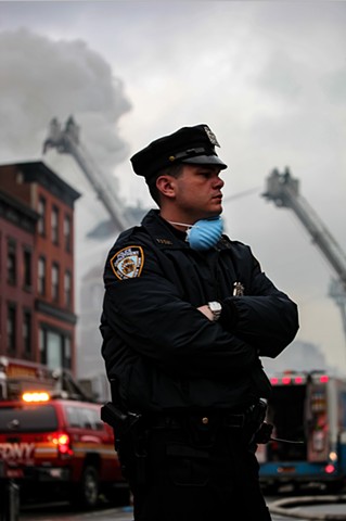 A first responder pauses at the scene of the Con Edison gas explosion and resulting fire in New York's East Village on March 26, 2015; an illegally-tapped gas main caused the explosion, completely obliterating a row of landmark residential buildings.