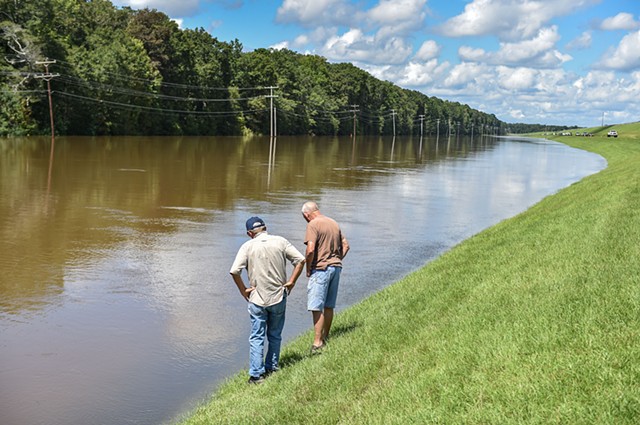 John Bethune, left, and a friend look at the fish that have come into the flooded Barnett Reservoir in Brandon, Miss., Sunday, August 28, 2022.