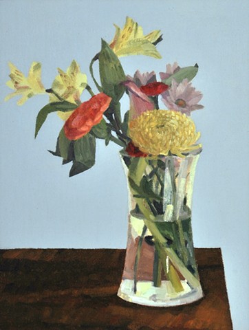 Yellow, red and purple flowers in a vase on a dark wood  table with a blue background
