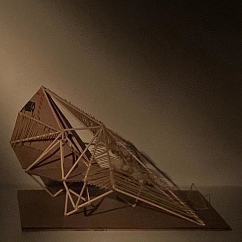 a small geometric sculpture made with rounds sticks and planes of cardboard