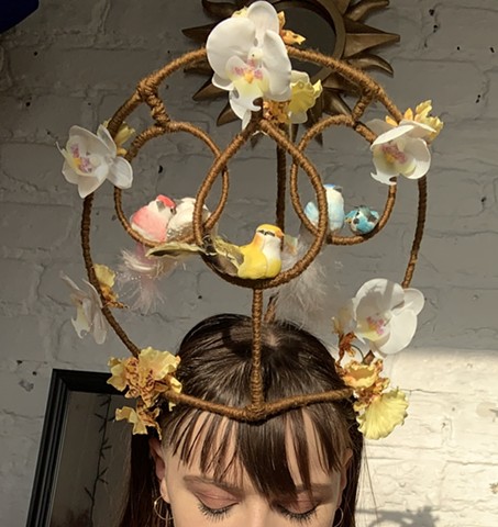 Wire frame hat featuring swinging perches for faux birds and flowers.