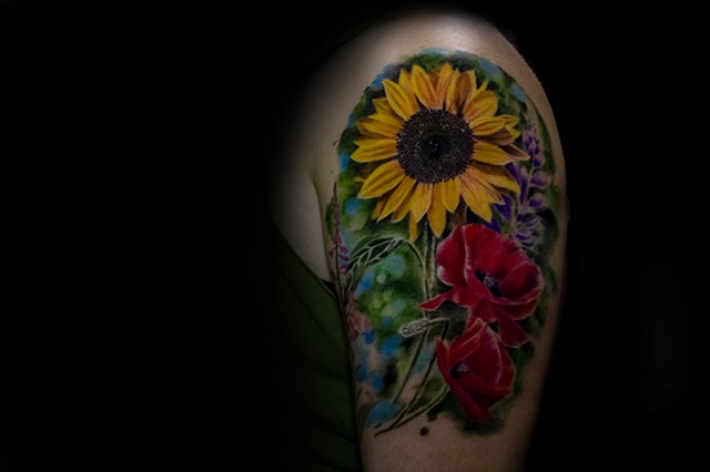 This is a really fun tattoo i was able to do of a Sunflower and some Poppies and other wildflowers to represent her home!