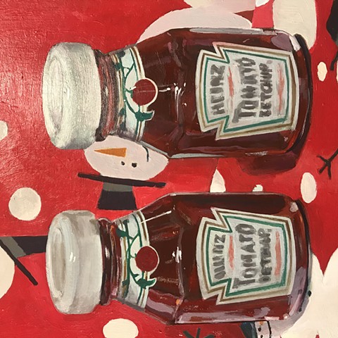 Primarily red and white, this image features two courtesy-sized Heinz ketchup bottles side by side. They sit an environment covered with Christmas wrapping paper featuring snowmen on a red field. 