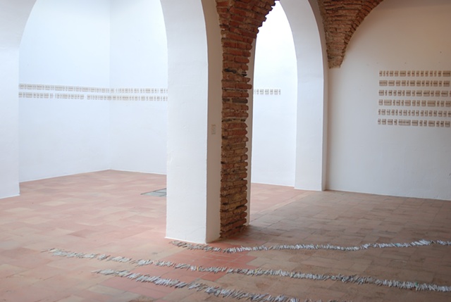 Exhibition Flying Carpet Prayers at El Psito, a Catholic prayer for world peace and a Jewish prayer for journeys. On the floor, rolled newspaper from Catalunya in a shape of Caadas Real