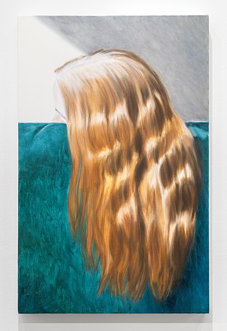 A woman's dyed red hair with visible roots draped over a green velvet couch