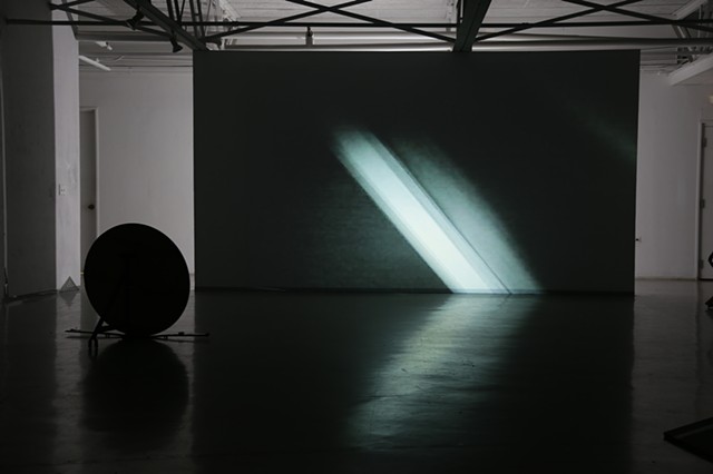 A freestanding wall with "New Bright" projected onto it. A still of a black image space has a bright white line at a 45-degree angle. On the left (Rear View, 2018) and on the right (Display System, 2018.) 