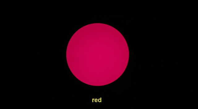 A large red circle on a black background with the caption red in the lower thirds of the screen. This is a still from a video piece titled 'Tell Me' (2016) 