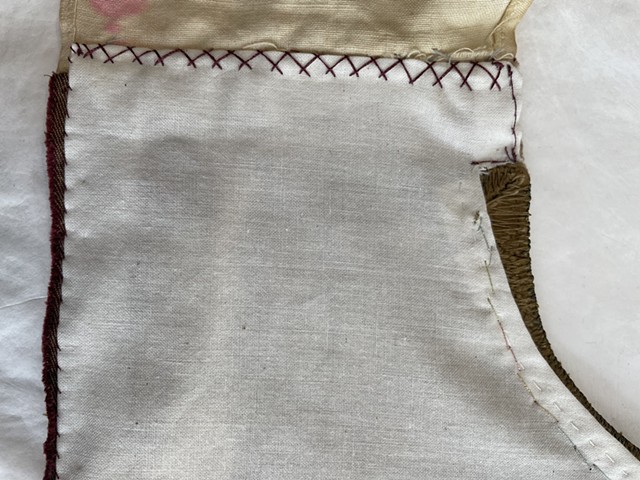 Close up, inside- criss cross backstitch at shoulders, running stitch and looping backstitch at collar, whip stitch on side