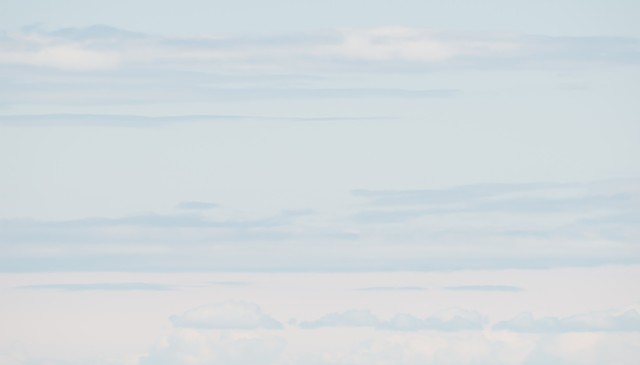A color photograph depicts a section of sky with pastel colors and lines of clouds.