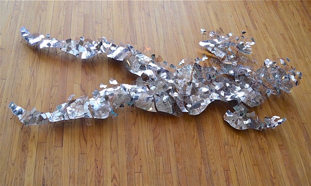 A contemporary figurative sculpture of mirrored plexiglass, wire and mica levitating up from the floor