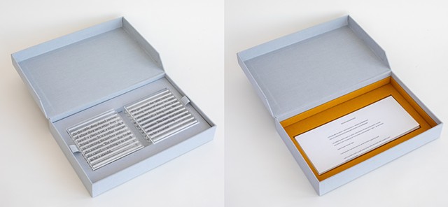 Two books in their box with the book tray pulled out to reveal a copy of the original PDF and the colophon