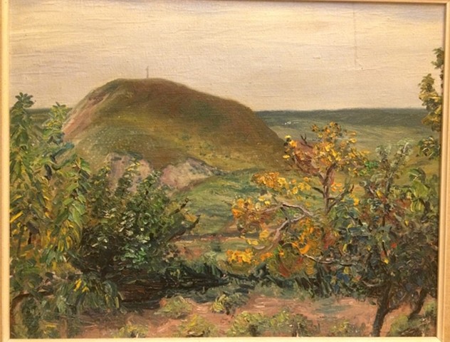 Hungarian landscape with trees in the foreground and hilly outcrop beyond.