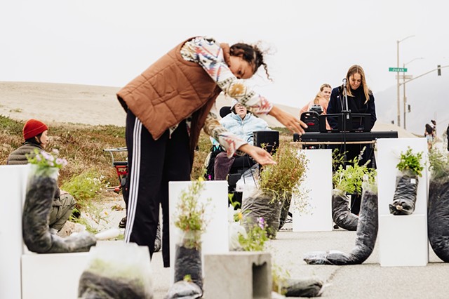 Shreen DeRyan dancing with and Sami Freeman playing music to the plants and a thank you for their year of growing and reaching out to the community (photo by David Enloe)