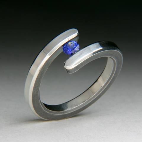 Bi-Pass Tension set ring, made of sterling silver with a high polish. Tension set stone is a blue natural sapphire.